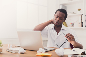 Overworked african-american employee in office, work with laptop