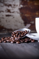 Coffee beans in metal scoop with blur old wood background