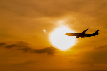 Fototapeta na wymiar silhouette airplane preparing for landing with sunset.