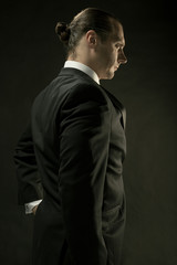 Fototapeta premium The attractive man in black suit on dark background
