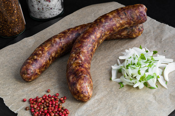 Two raw sausages with onion and spices