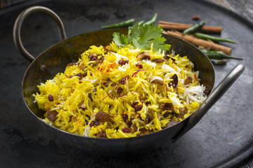 Indian vegetarian biryani with nuts and raisins as close-up in a korai