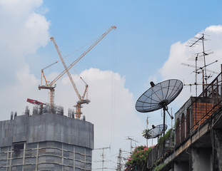 Old Satellite disc against Construction tower canes over construction site. Building development.