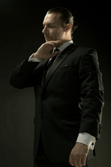 The attractive man in black suit on dark background