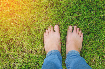 Barefoot on green grass field with orange light