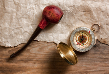 compass and a tobacco pipe on a wooden board