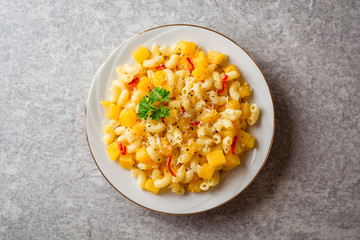 Pasta with pumpkin, chili and cheese in plate on stone background