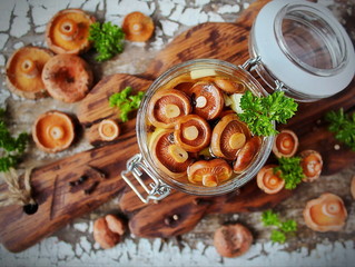 marinated mushrooms saffron milk caps in a glass jar and fresh mushrooms on a wooden Board