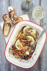 Fried John Dory fish fillet with vegetable and baguette as top-view in a roasting tin