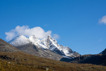 Mountain scenery with snow on the high peaks against blue sky background