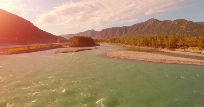 4k (UHD) aerial view. Low flight over fresh cold mountain river at cloudy summer morning. Green trees and sun rays on horisont. Fast horizontal movement