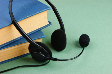 Headphones with a microphone and a stack of books on a green background