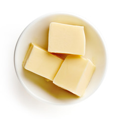 Butter pieces in bowl isolated on white background, top view