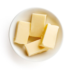 Butter pieces in bowl isolated on white background, top view