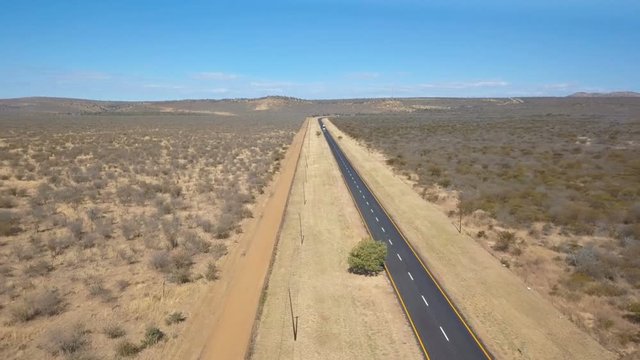 Asphalt road with wide fire break in arid bush veld aerial shot