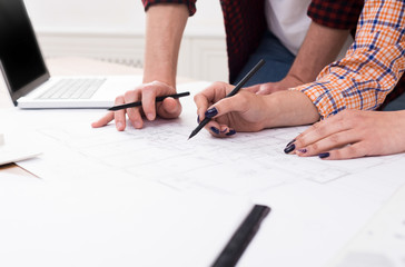 Unrecognizable architects discussing building plan