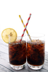 Softdrink with ice cubes, lemon and straw in glass