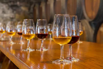 Fotobehang glasses of red and white port wine with barrels in background, wine degustation © neirfy