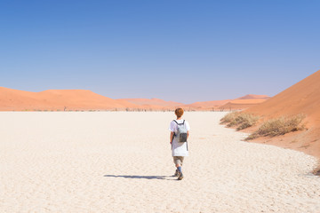 Tourist walking on the scenic dunes of Sossusvlei, Namib desert, Namib Naukluft National Park, Namibia. Adventure and exploration in Africa.