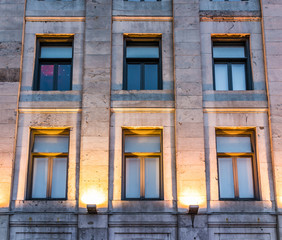 Old town area brick building illuminated by yellow lights and lanterns by street in evening outside in Quebec region city