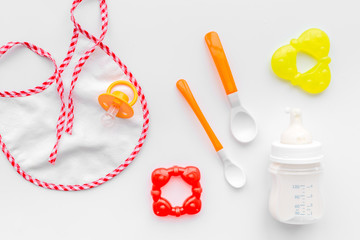 preparation of mixture baby feeding with infant formula powdered milk in bottle with bib on white background top view