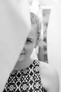 Black And White Of Teen Girl Hiding Behind Clean Laundry Hanging On A Washing Line