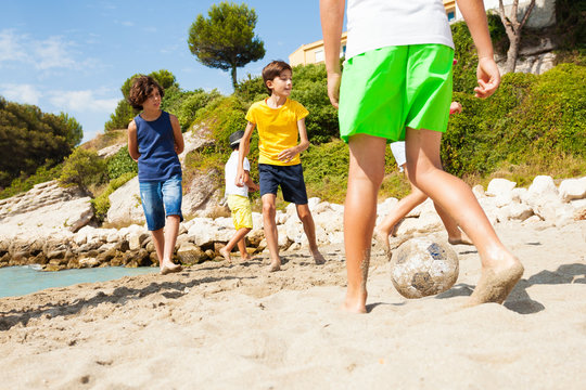 Kids playing football barefoot on sandy beach