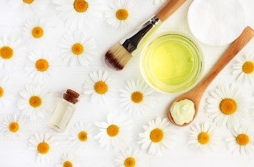 Chamomile essential oil cosmetic products, top view background white fresh flowers, facial mask and tonic.