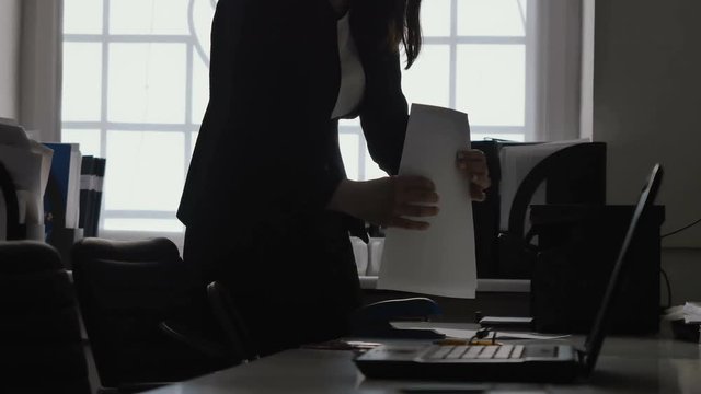 Silhouette of businesswoman staple documents with a stapler in office