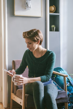 Young Woman Stitting in a Chair and Using Phone