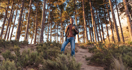 Fototapeta premium Smiling young African man standing on a forest trail