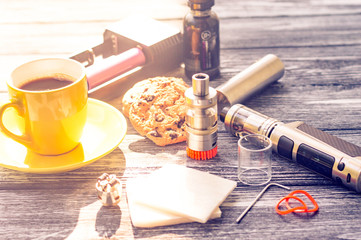 Still life with electronic cigarette with botle and coffe on the wooden background
