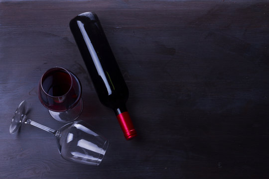 Bottle of red wine and one wine glasses on table with copy space
