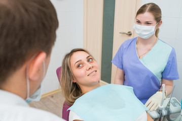 Fototapeta premium Woman patient sitting at dental chair, smiling and looking at doctor in dentist clinic.
