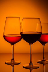Set of wine glasses with red and rose wine on orange background