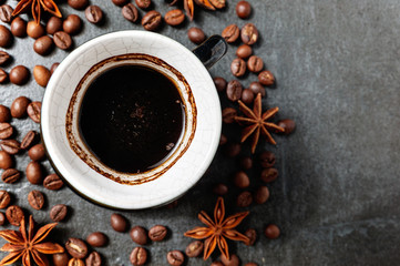Coffee cup with coffee beans on stone table background with star anise.