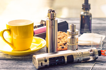 Obraz na płótnie Canvas Still life with electronic cigarette with botle and coffe on the wooden background