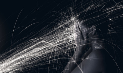 Long exposure photo of woman blocking glowing sparks artistic conversion