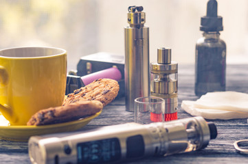 Still life with electronic cigarette with botle and coffe on the wooden background