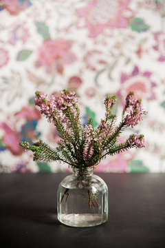 Flowers in small bottle, in front of a floral background