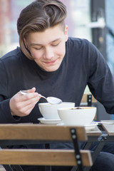 Young man eating bowl of soup