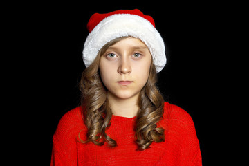 A sad girl in a red sweater and a Santa Claus hat looks at the viewer.