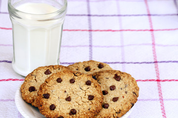 refreshment, eating snack: glass of milk and chocolate chip cookies on table cloth with copy space