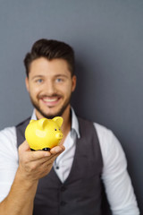 mann hält ein sparschwein in der hand und lacht