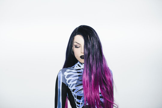 Woman with halloween make-up, costume and colored hair shot with harsh, front light