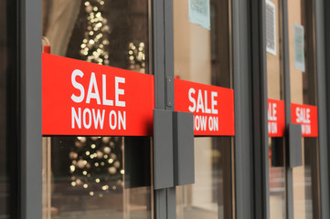 Signs on shop doors indicating "Sale Now On"