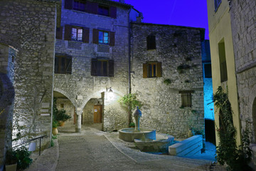 Narrow cobbled street in old town Peille at night, France.
