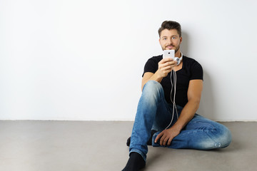 Fototapeta premium mann sitzt auf dem fußboden und hört musik