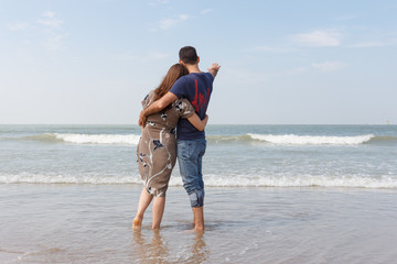 Couple in love standing on the beach looking into the distance.
