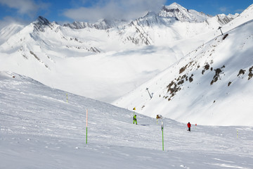 Skier and snowboarder downhill on freeride trace and mountains in clouds